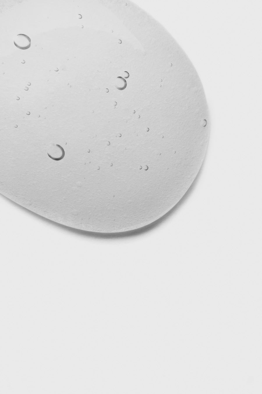 A clear drop of serum gel on a pale surface